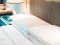 Cama de hotel con almohadas blancas y cabecero de mimbre. Una guía para saber como elegir un colchon.