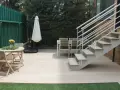 Escaleras exteriores casas de campo, con mesa y sillas de madera, sombrilla y valla verde.
