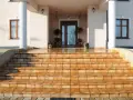 Amplias escaleras exteriores para casas de dos pisos, con escalones de baldosas naranjas que conducen a una entrada principal.