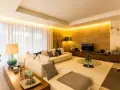 Salón moderno con sofá blanco, mesa de centro de cristal y **iluminación indirecta** cálida que realza la pared de piedra.