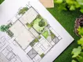 Plano detallado de paisajistas de jardines, con áreas verdes, caminos y estructuras, sobre césped artificial.
