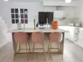 Elegantes cocinas con isla, tres taburetes rosas y dorados invitan a disfrutar.
