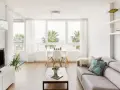 Acogedor salón nórdico rústico con sofá gris, mesa de centro de madera y vistas a palmeras.