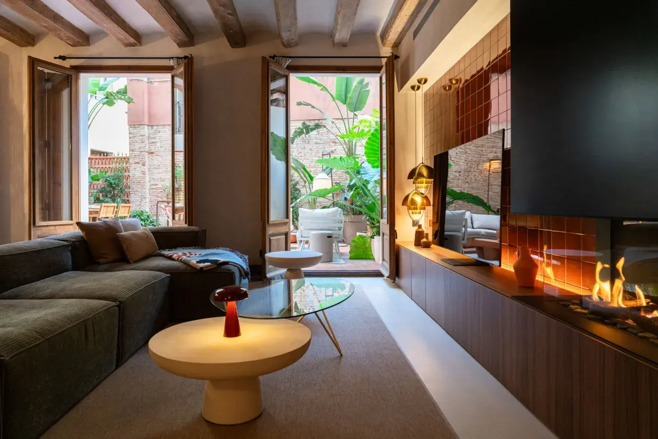 Acogedor salón con chimenea y acceso a un patio interior exuberante. Un ejemplo de diseño de interiores moderno y funcional.