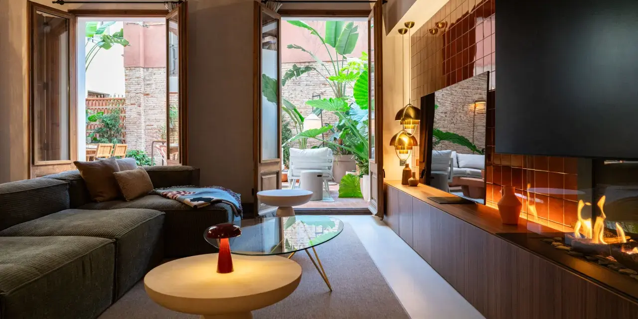 Acogedor salón con chimenea y acceso a un patio interior exuberante. Un ejemplo de diseño de interiores moderno y funcional.