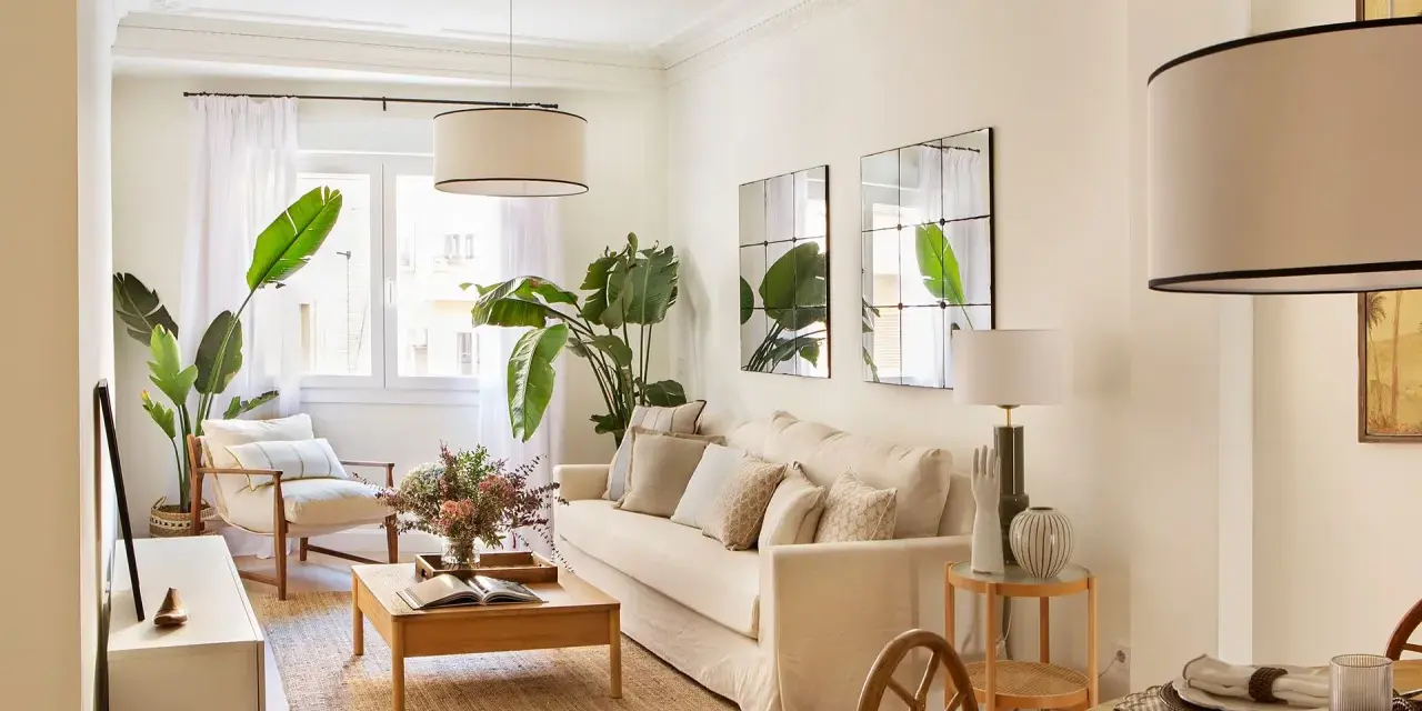 Elegante decoracion salon con sofá beige, plantas verdes, mesa de centro de madera y sillón.