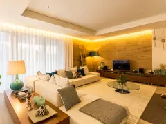 Salón moderno con sofá blanco, mesa de centro de cristal y **iluminación indirecta** cálida que realza la pared de piedra.