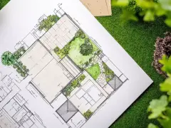Plano detallado de paisajistas de jardines, con áreas verdes, caminos y estructuras, sobre césped artificial.