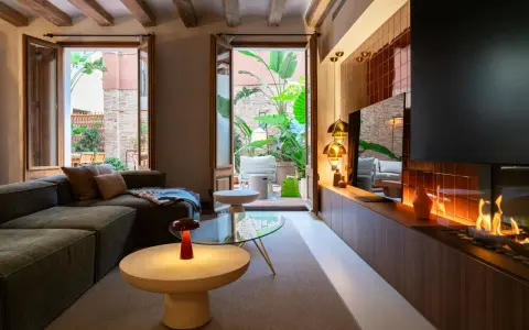 Acogedor salón con chimenea y acceso a un patio interior exuberante. Un ejemplo de diseño de interiores moderno y funcional.