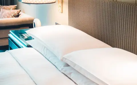Cama de hotel con almohadas blancas y cabecero de mimbre. Una guía para saber como elegir un colchon.