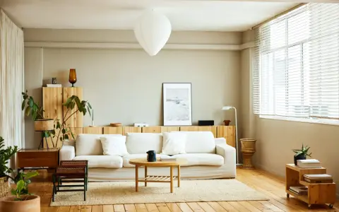 Salones nórdicos con sofá blanco, mesa de centro de madera y estanterías de pino. Luz natural entra por la ventana.