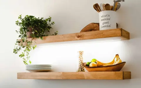Estantes de madera con iluminación LED oculta, ideal para saber como colocar tiras led en estantes. Exhiben plantas, vajilla y frutas.
