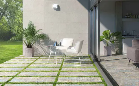 Modernos suelos para patios interiores con un diseño de baldosas y césped. Un espacio acogedor con mesa y sillas blancas.