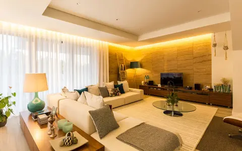 Salón moderno con sofá blanco, mesa de centro de cristal y **iluminación indirecta** cálida que realza la pared de piedra.