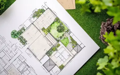 Plano detallado de paisajistas de jardines, con áreas verdes, caminos y estructuras, sobre césped artificial.