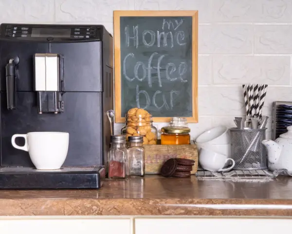 Máquina de café, taza, galletas y un letrero que dice "my Home Coffee bar". Todo listo para disfrutar de un momento de relax en tu zona de cafe en la cocina.
