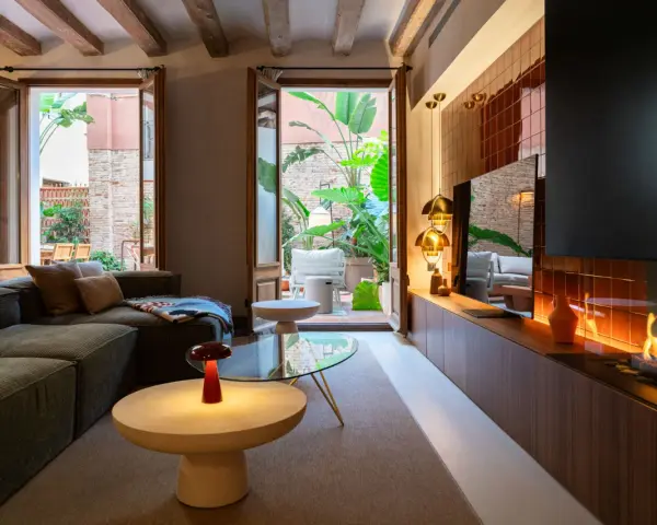 Acogedor salón con chimenea y acceso a un patio interior exuberante. Un ejemplo de diseño de interiores moderno y funcional.