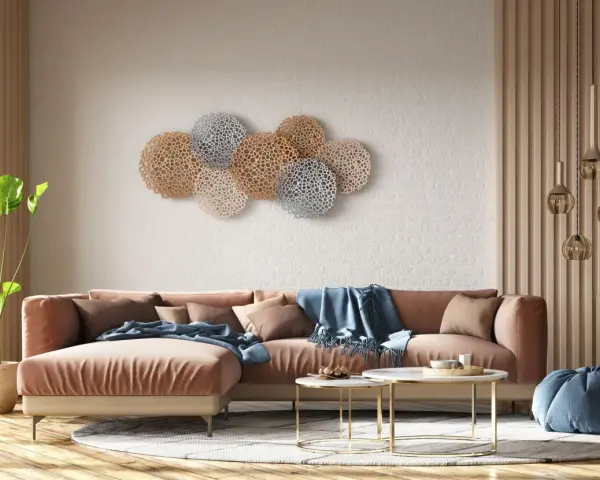 Decoración pared salón original con un sofá terracota y arte de pared circular en tonos dorados y plateados.