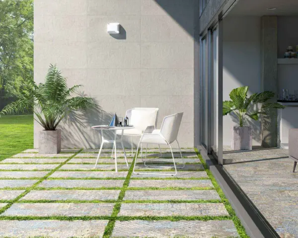 Modernos suelos para patios interiores con un diseño de baldosas y césped. Un espacio acogedor con mesa y sillas blancas.