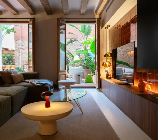 Acogedor salón con chimenea y acceso a un patio interior exuberante. Un ejemplo de diseño de interiores moderno y funcional.