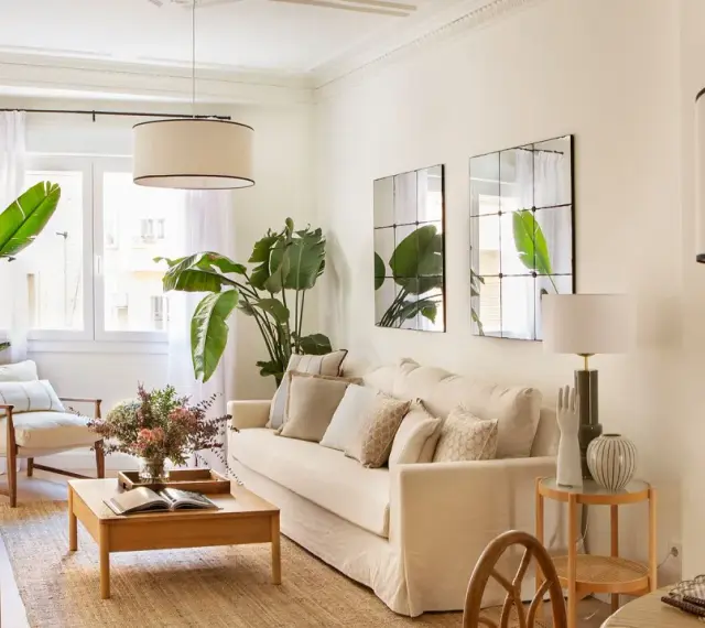 Elegante decoracion salon con sofá beige, plantas verdes, mesa de centro de madera y sillón.