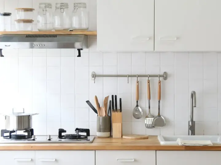 Diseños de cocinas pequeñas y sencillas: encimera de madera, campana extractora, utensilios colgados y un fregadero blanco.