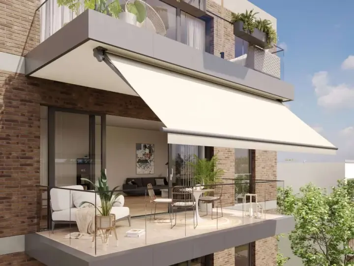 Balcón moderno con sofá, mesa y sillas, protegido por uno de los tipos de toldos más elegantes.