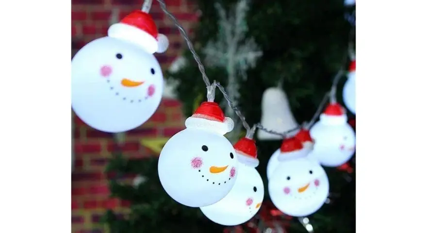 Luces de muñecos de nieve con gorros rojos, perfectos adornos navideños caseros para exterior, iluminan la noche festiva.