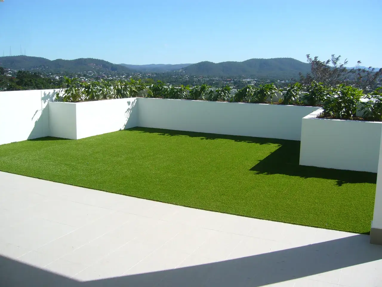 Terraza con c&eacute;sped artificial verde vibrante, ideal para aprender como colocar c&eacute;sped artificial y disfrutar de vistas panor&aacute;micas.