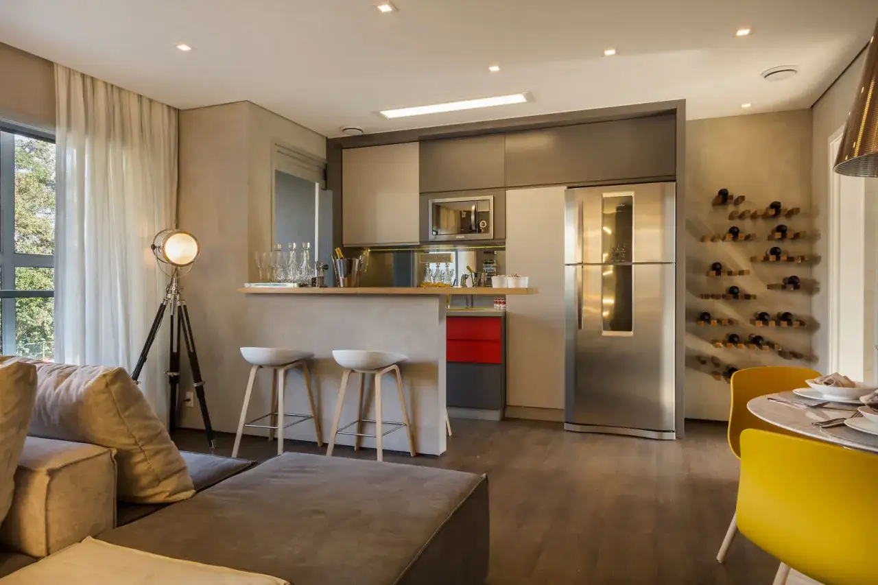 Espacio moderno de cocina sal&oacute;n comedor de 30 m2 con barra, sof&aacute;s, nevera y estanter&iacute;a de vinos.