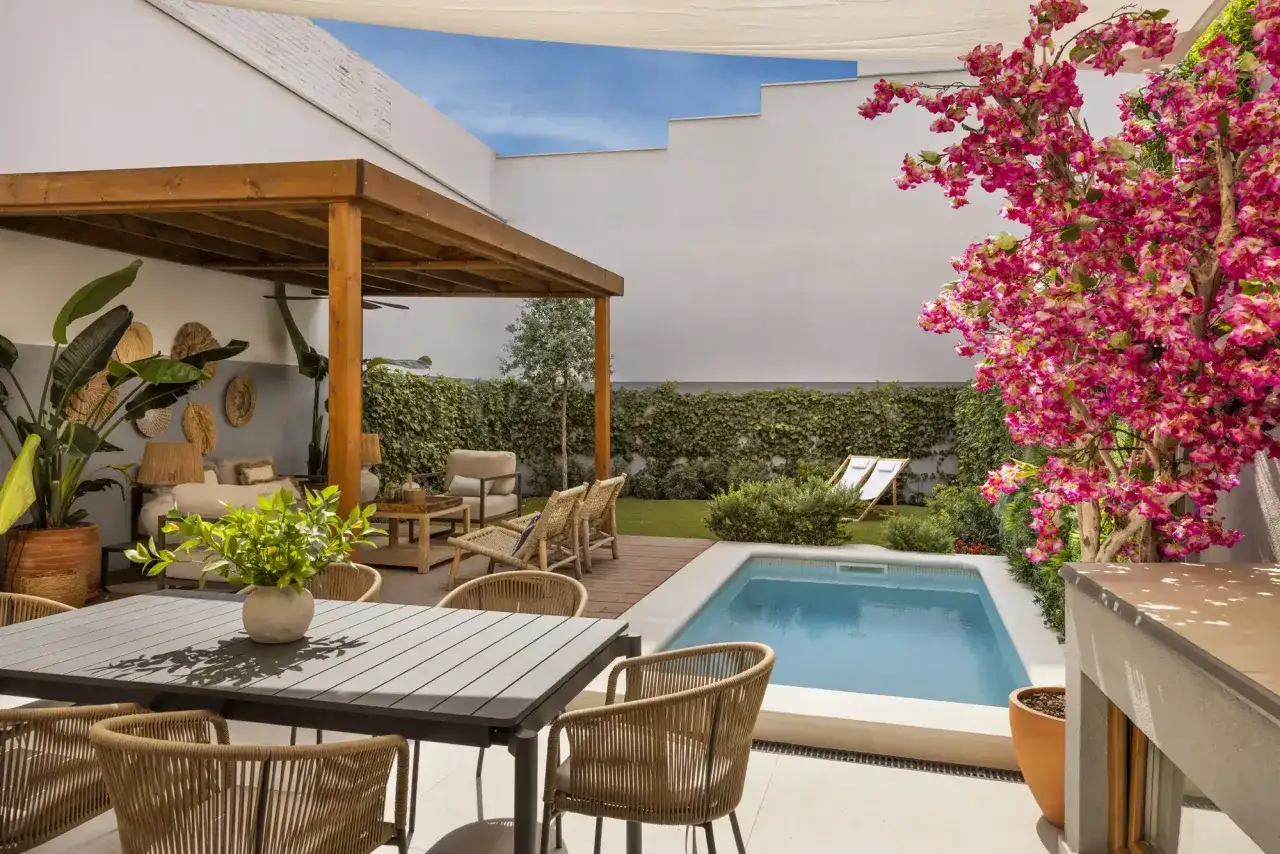Un patio moderno con piscina, pérgola de madera, zona de estar y comedor, ideal para saber como decorar un patio con piscina y disfrutar del verano.