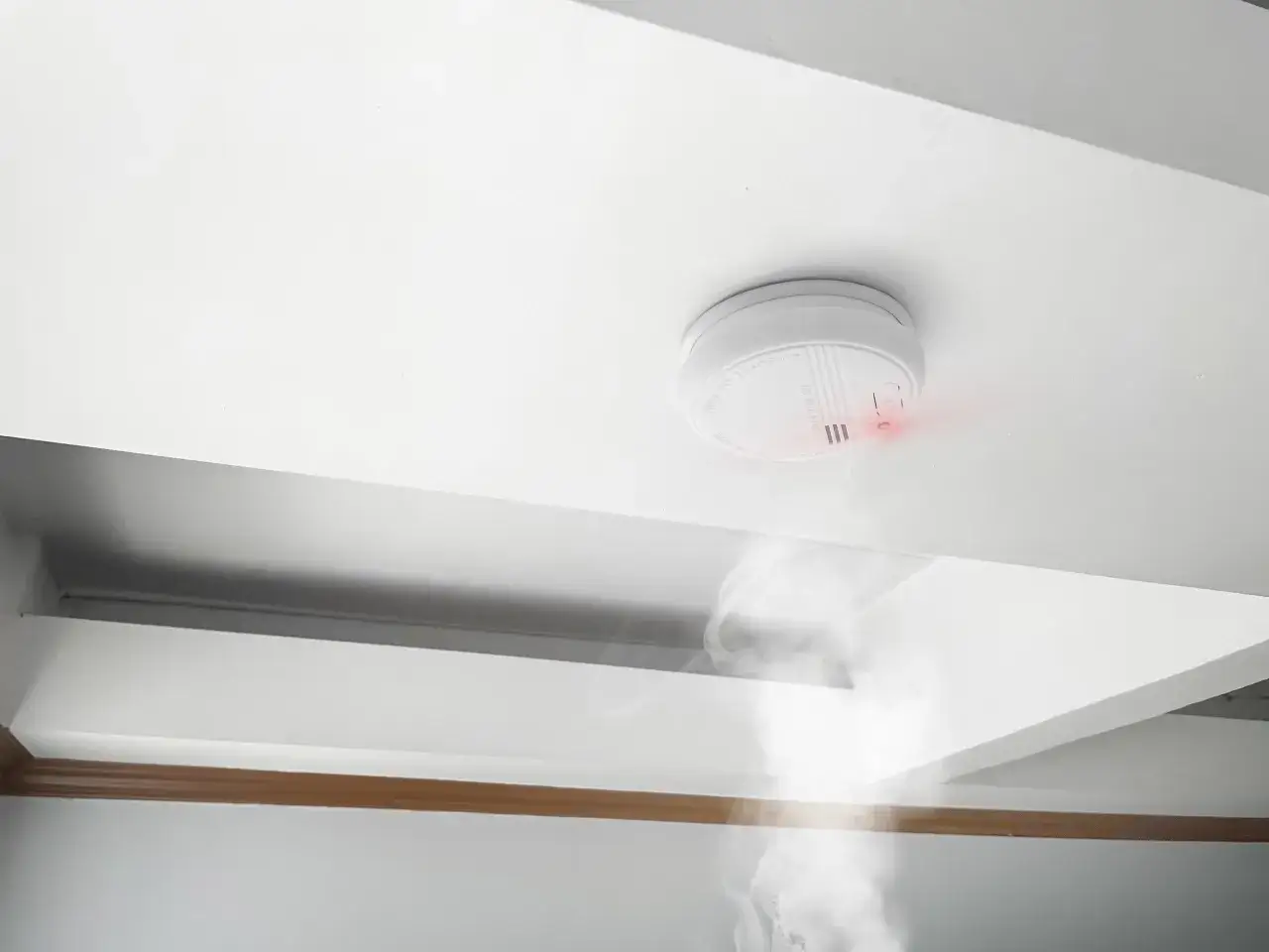 Detector de humo activado, emitiendo una luz roja y humo. Cumpliendo la normativa de detectores de humo para tu seguridad.