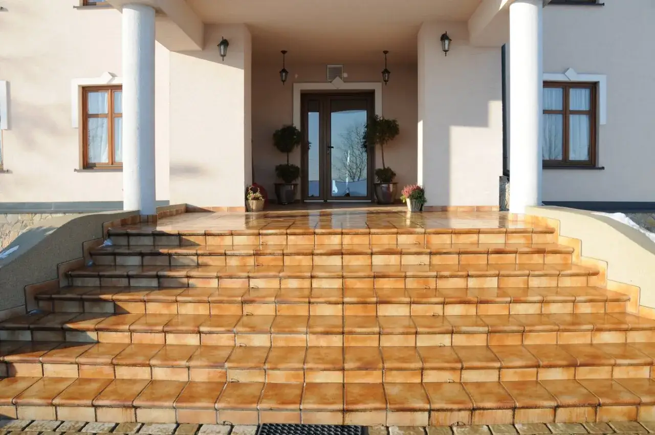 Amplias escaleras exteriores de casas de campo, con escalones de baldosas anaranjadas que invitan a subir a la entrada principal.