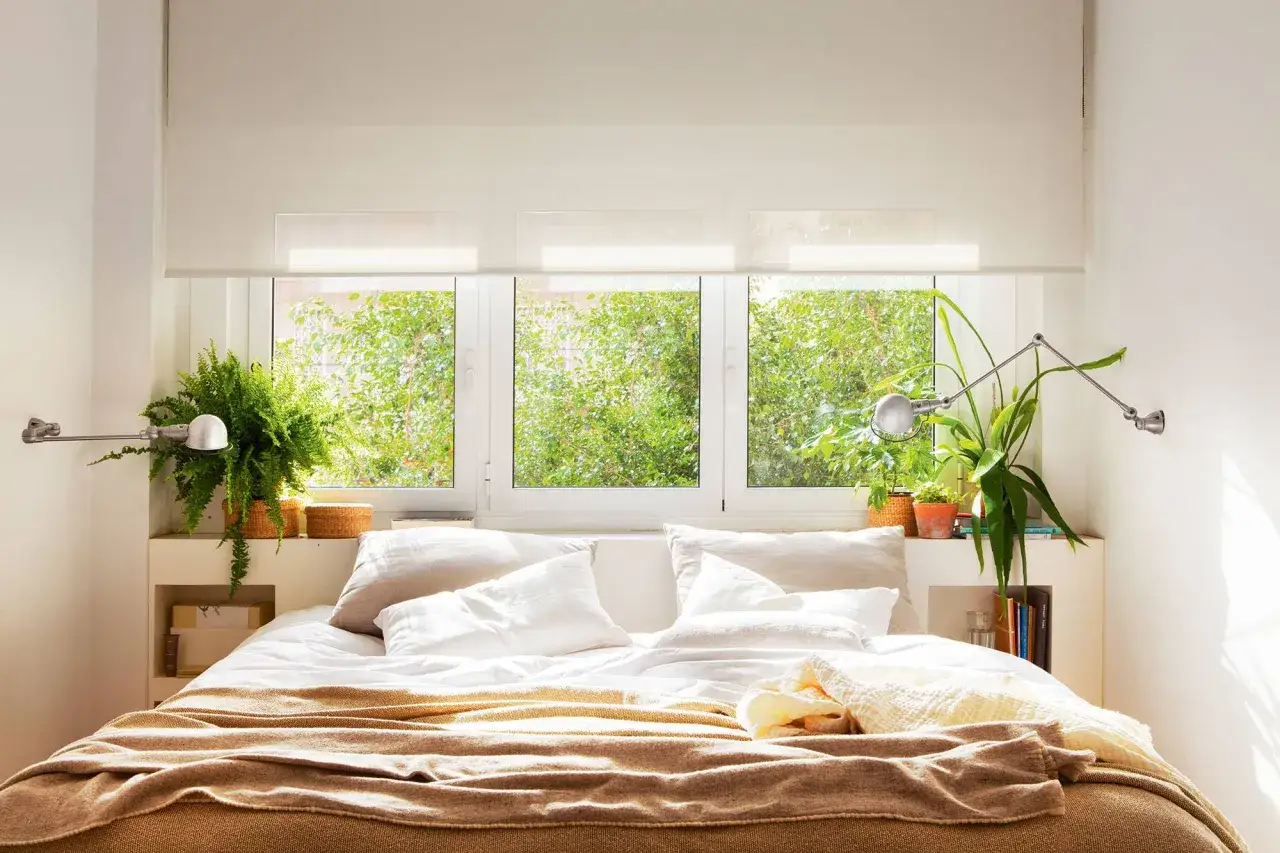 Cama acogedora con plantas para dormitorio, rodeada de luz natural y vegetación exuberante.