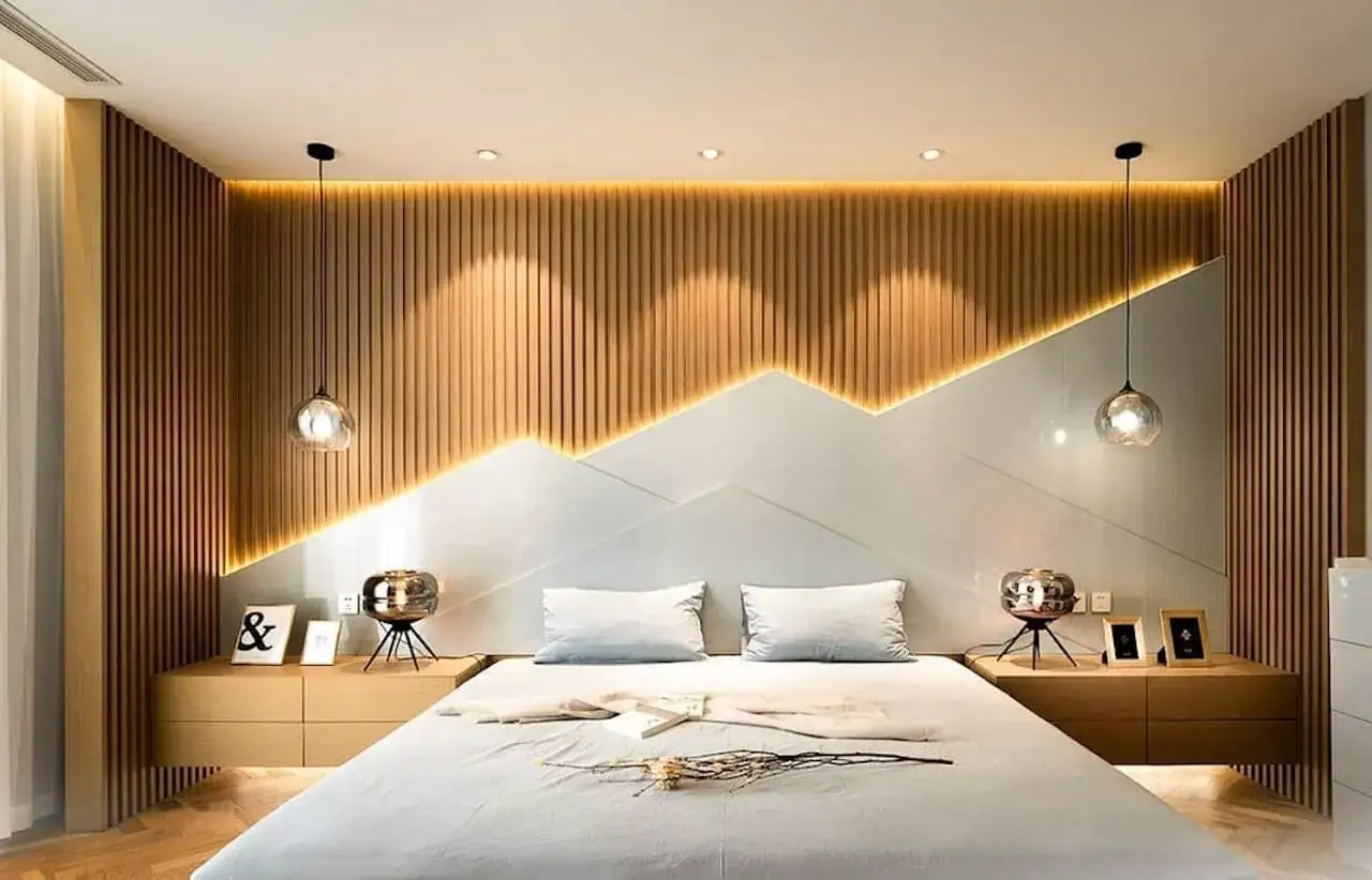 Cabecero de cama moderno con iluminaci&oacute;n con tiras led que resalta las lamas de madera y el dise&ntilde;o geom&eacute;trico.