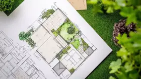 Plano detallado de paisajistas de jardines, con áreas verdes, caminos y estructuras, sobre césped artificial.