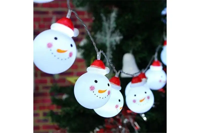Luces de muñecos de nieve con gorros rojos, perfectos adornos navideños caseros para exterior, iluminan la noche festiva.