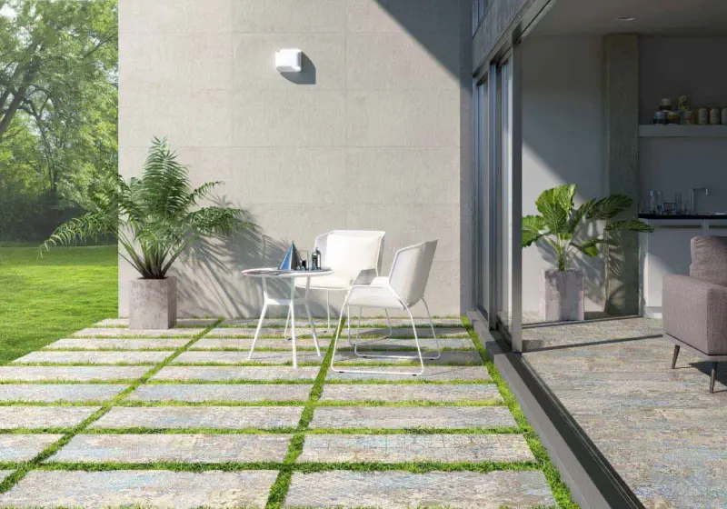 Modernos suelos para patios interiores con un diseño de baldosas y césped. Un espacio acogedor con mesa y sillas blancas.